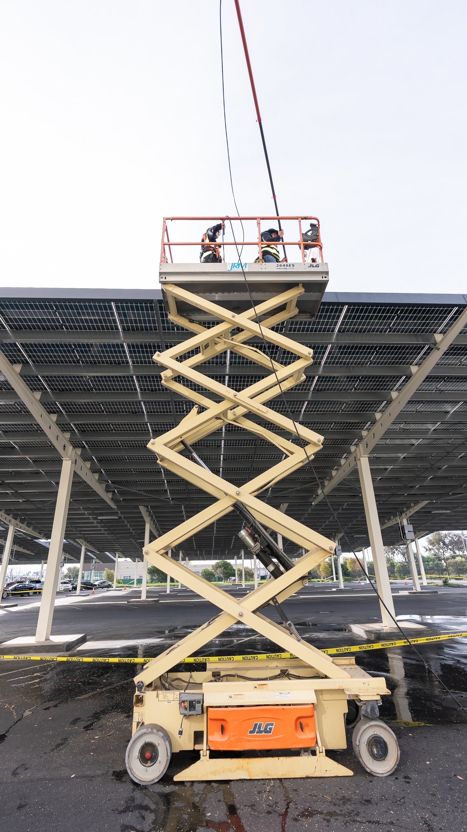 Professional solar cleaning team using a lift to access high roof solar panels safely